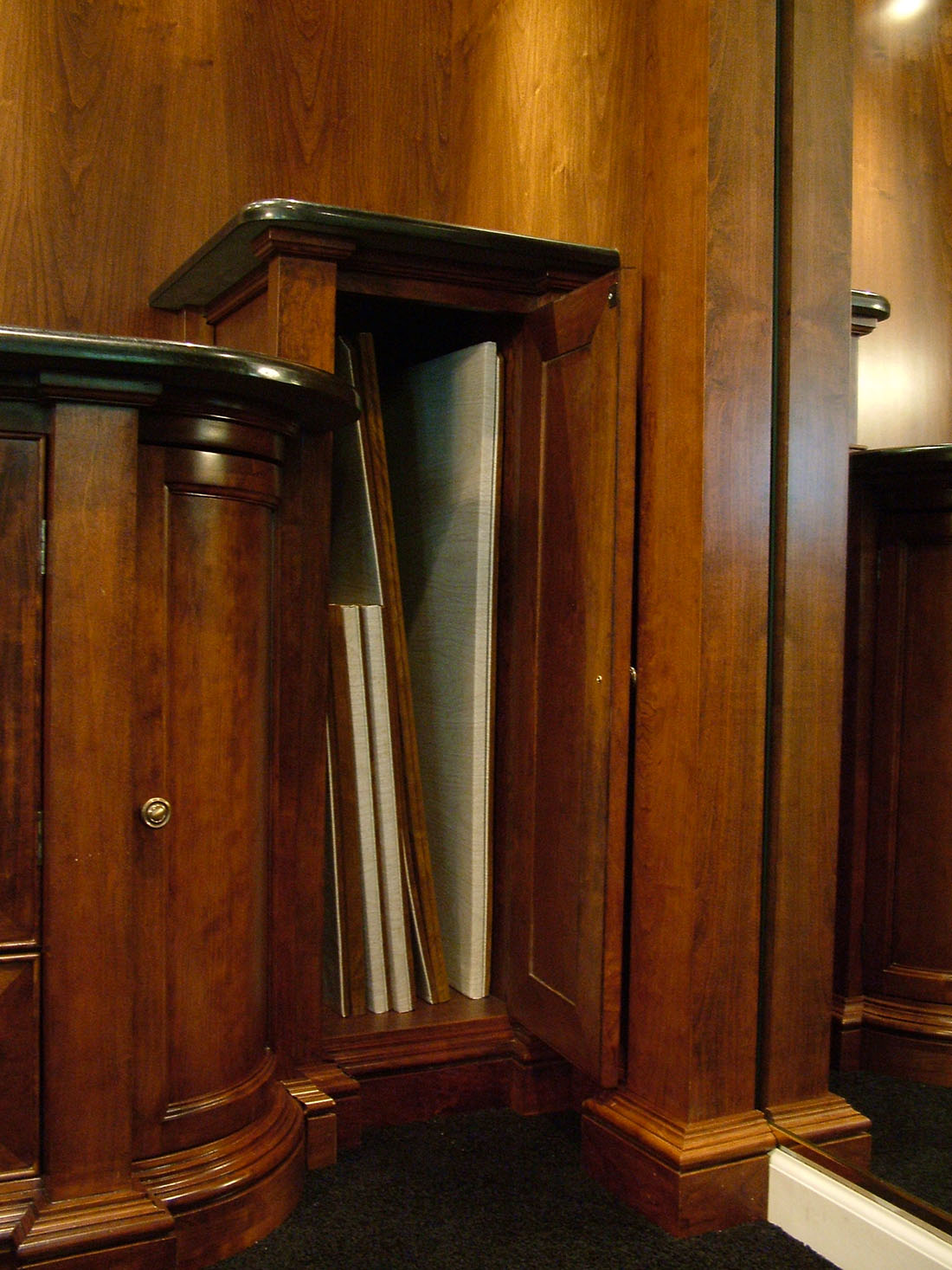 Door of tall cabinet section open to reveal tall table pads inside